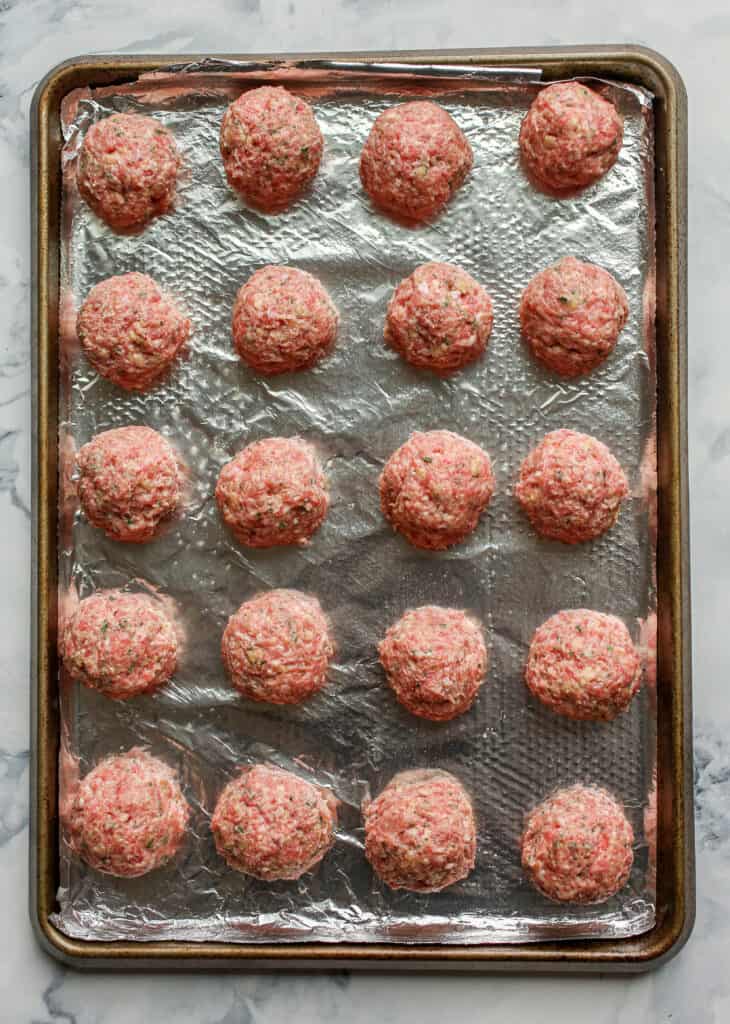 Raw meatballs on baking sheet.
