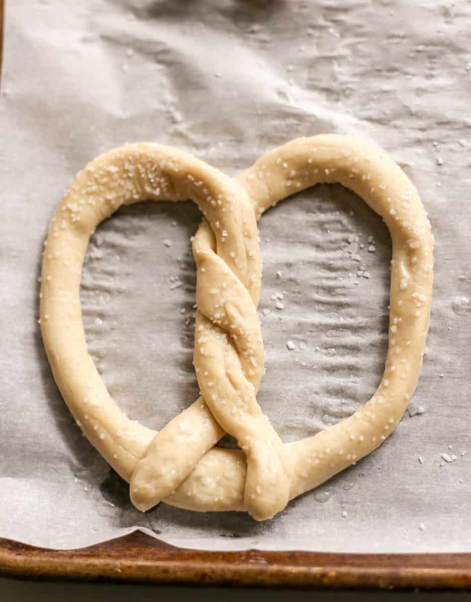 Pretzel dough shaped on parchment paper before baking.