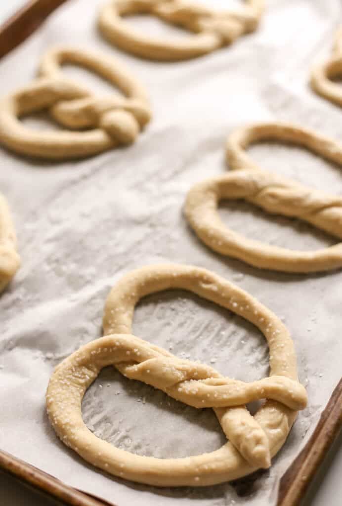 Pretzel dough shaped on parchment paper before baking.