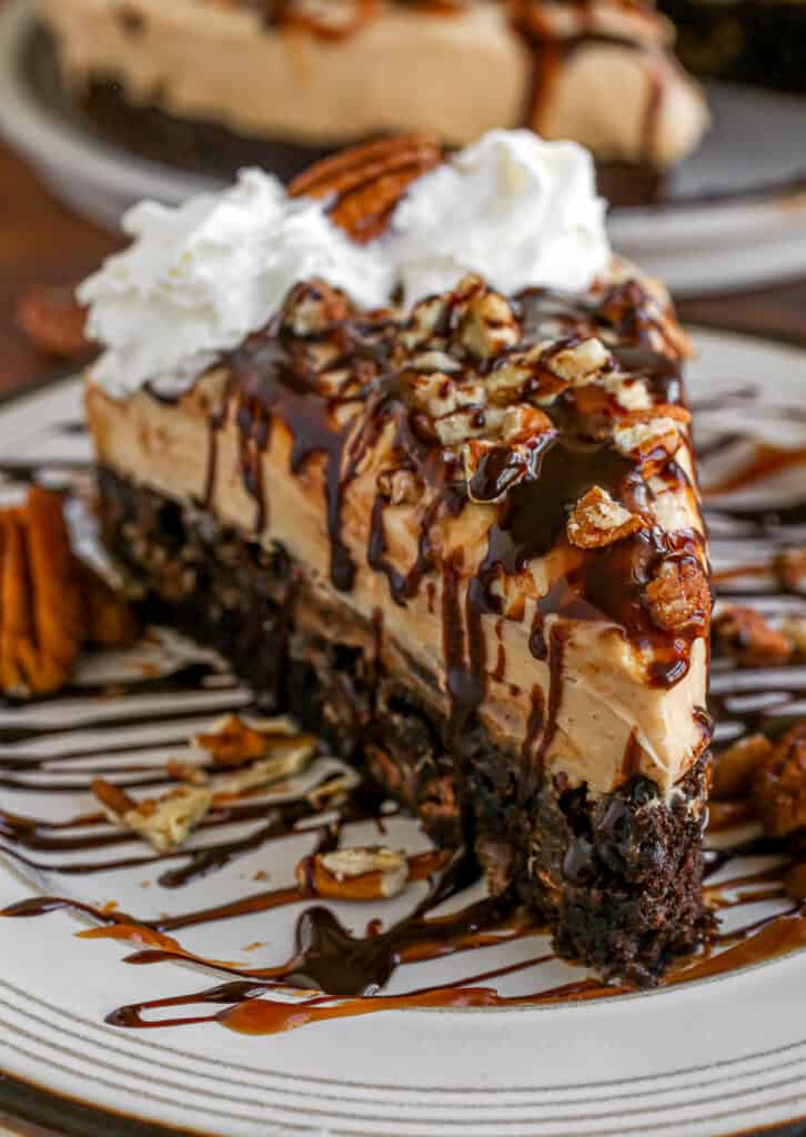 Close up of caramel turtle cheesecake slice on a plate.