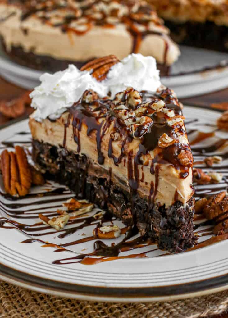 Caramel turtle cheesecake slice on a plate with drizzle.