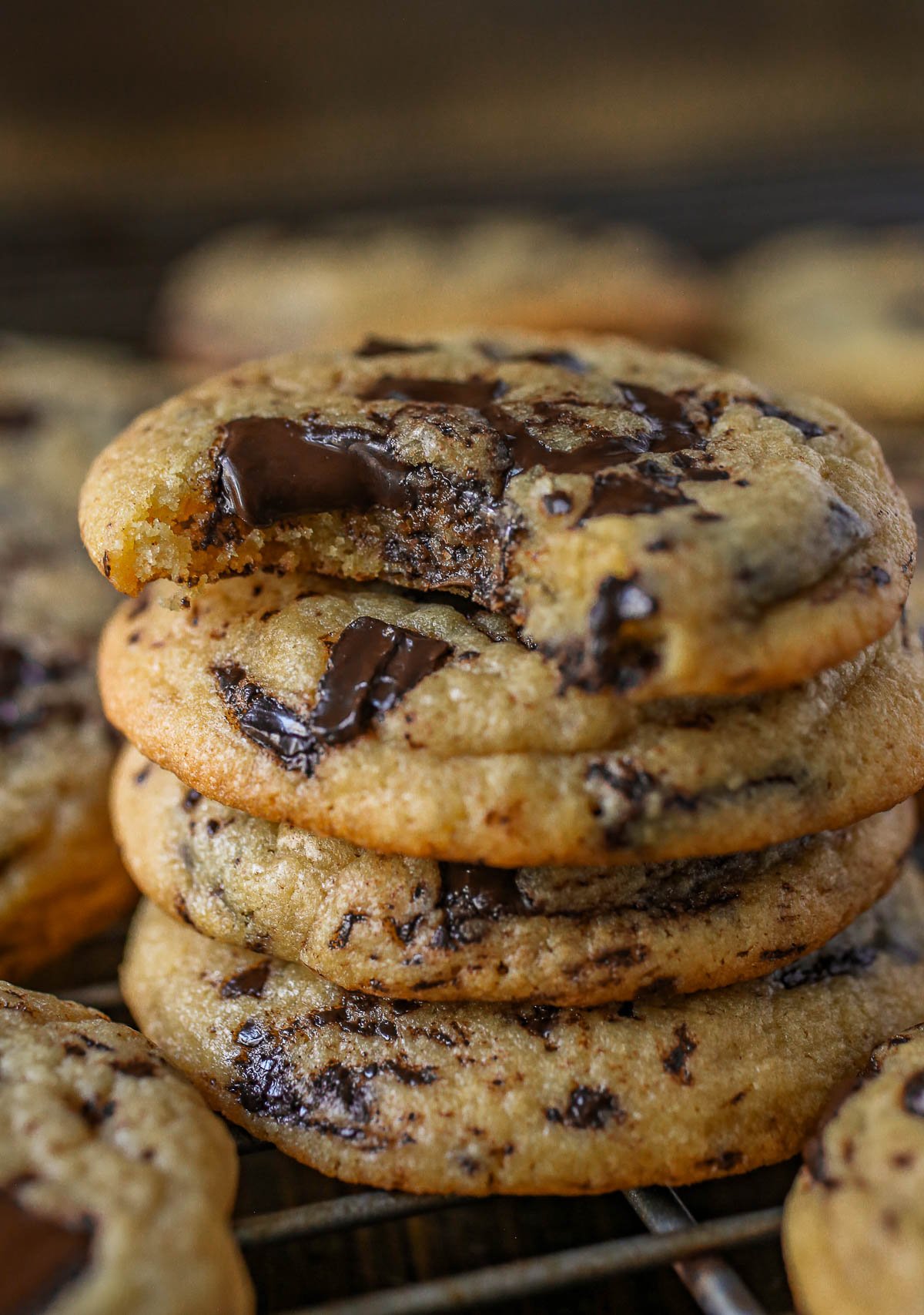 Stack of chocolate chip pudding cookies on a cooling rack with a bite taken out of the top cookie.